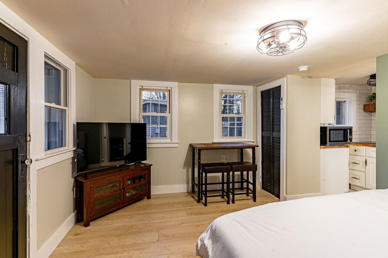 A bedroom with a bed, a TV, a dresser, and a desk with a chair.