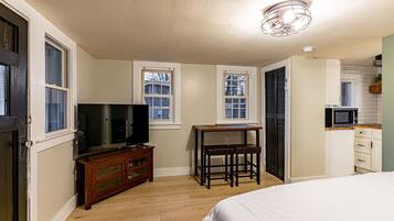 A bedroom with a bed, a TV, a dresser, and a desk with a chair.