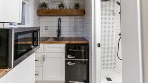 A compact kitchen with white cabinets, a wooden countertop, a built-in microwave, and a dishwasher. - Cozy Cabin in a rural setting #12 in Temple NH (Temple)