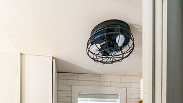 A compact kitchen with white cabinets, a microwave, and a window with blinds.