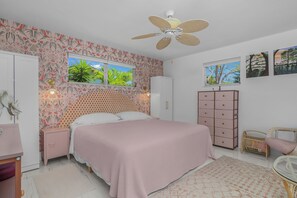 Une chambre à coucher comprenant un lit, une armoire, une table de chevet, un ventilateur de plafond et une fenêtre donnant sur un paysage verdoyant.