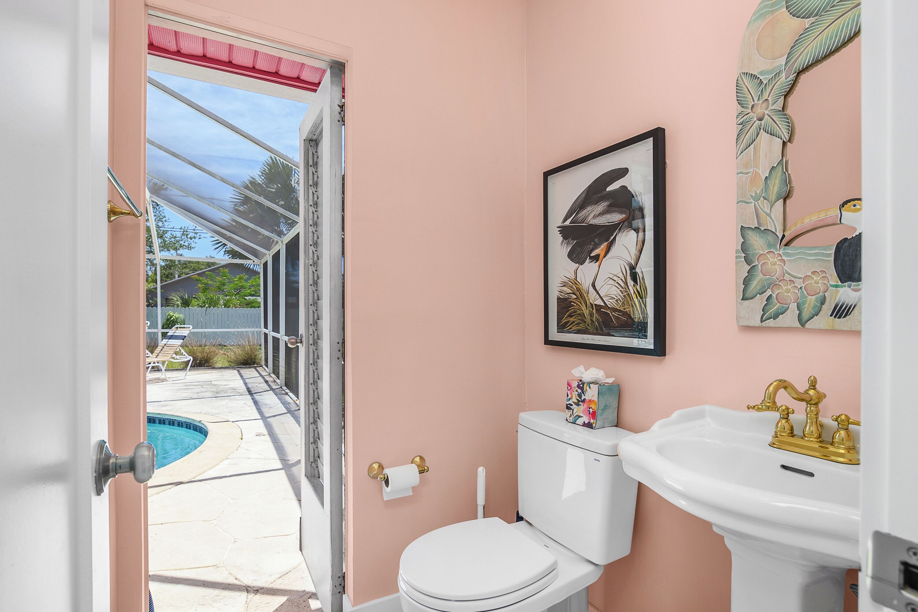 A bathroom with a toilet, sink, and a framed artwork on the wall.