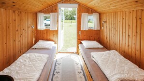 Eine Holzhütte mit zwei Einzelbetten und Blick ins Freie.
