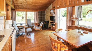 Eine gemütliche Küchenzeile im Blockhausstil mit Holzböden, einem Essbereich und einem Kamin.