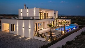 Uma casa moderna de dois andares com piscina, janelas amplas e vista para a paisagem ao redor.