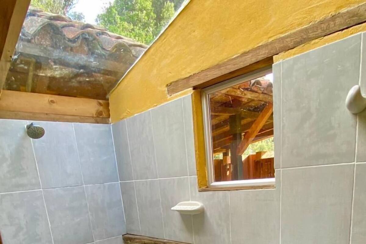 Een badkamer met een douche, een wastafel en een raam.
