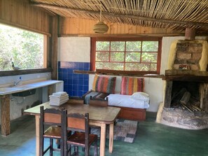 Una habitación rústica con una mesa de madera, sillas, un banco, un lavabo y una chimenea.
