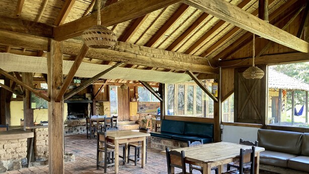 Un comedor de planta abierta con vigas de madera rústica, paredes de piedra y piso de ladrillo.
