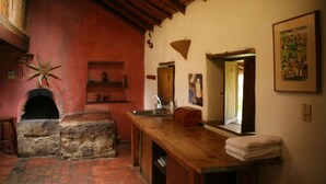 Una cocina rústica con un horno de piedra, encimera de madera y suelo de ladrillo rojo.