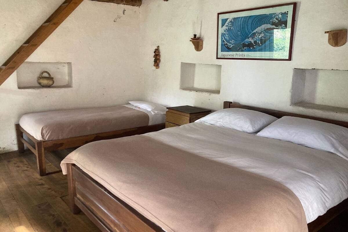 Een kamer met twee houten bedden, een houten plafond en een ingelijst schilderij aan de muur.