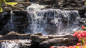 Ein Wasserfall, Felsen und ein Gebäude mit vielen Fenstern.