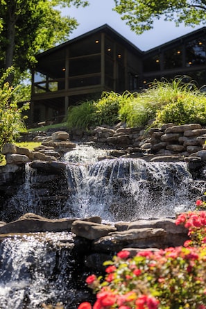 A waterfall, rocks, and a building with multiple windows.