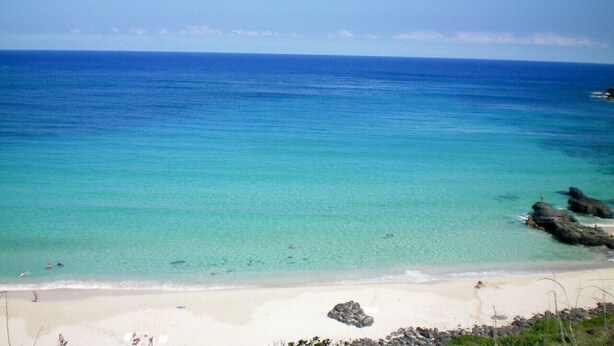 A beach with clear turquoise water, white sand, and rocky outcrops. - Spacious 1 Bedroom Condo at Turtle Bay (Kahuku)