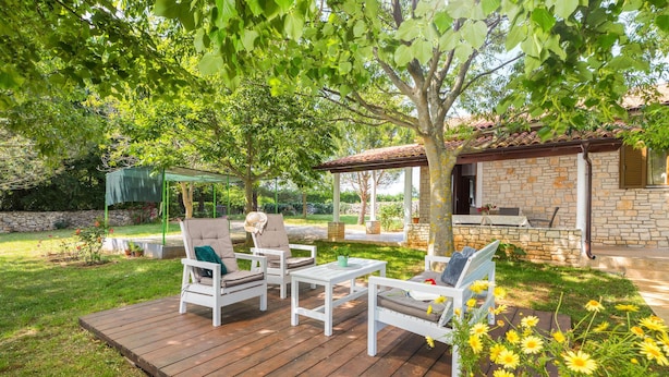 An outdoor patio with white furniture, a stone building, and a garden with yellow flowers. - Pet friendly home in Svetvincenat (Svetvincenat)