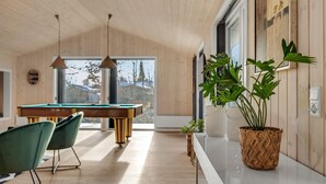 A modern interior with a pool table, green chairs, and a large potted plant. - 5 bedroom amazing home in Glesborg (Glesborg)
