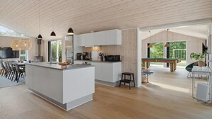 A modern kitchen with a central island, white cabinetry, and a large window. - 5 bedroom amazing home in Glesborg (Glesborg)