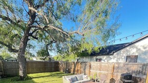 A backyard with a wooden deck, outdoor furniture, a barbecue area, and a stone pathway. - Janie’s cozy cottage minutes from Texas A&M Kingsville (Kingsville)