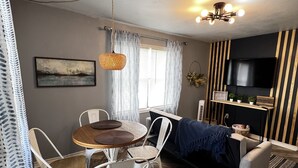 A modern living room with a dining area, a sofa, and a TV mounted on the wall. - Janie’s cozy cottage minutes from Texas A&M Kingsville (Kingsville)