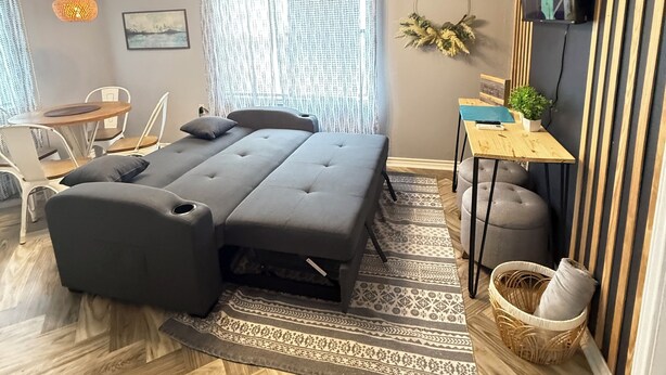 A modern bedroom with a sofa bed, a small desk, a TV, and a window with curtains. - Janie’s cozy cottage minutes from Texas A&M Kingsville (Kingsville)