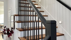 A modern staircase with wooden steps and black metal railings, leading to an upper floor. - Spacious 4BR Retreat, Sleeps 10, Backyard + Near Dallas (Dallas)