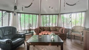 A spacious room with a large window, a leather armchair, a sofa with patterned cushions, a wooden coffee table, and a wicker chair. - Beautiful home in Chaam with WiFi (Chaam)