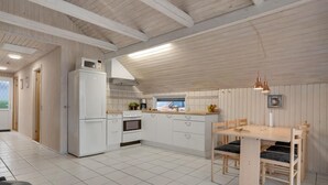 A modern kitchen with white cabinetry, a built-in oven, and a dining area with a wooden table and chairs. - Gorgeous home in Hejls with WiFi (Hejls)