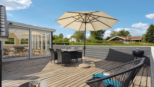 An outdoor deck with a table and chairs, a grill, and a large umbrella. - Gorgeous home in Hejls with WiFi (Hejls)