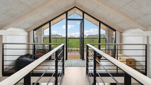 A modern loft bedroom with a large skylight, a wooden staircase, and a view of a green field. - Gorgeous home in Skjern with kitchen (Skjern)