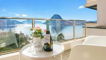 A balcony with a table, a bottle of wine, and two glasses.