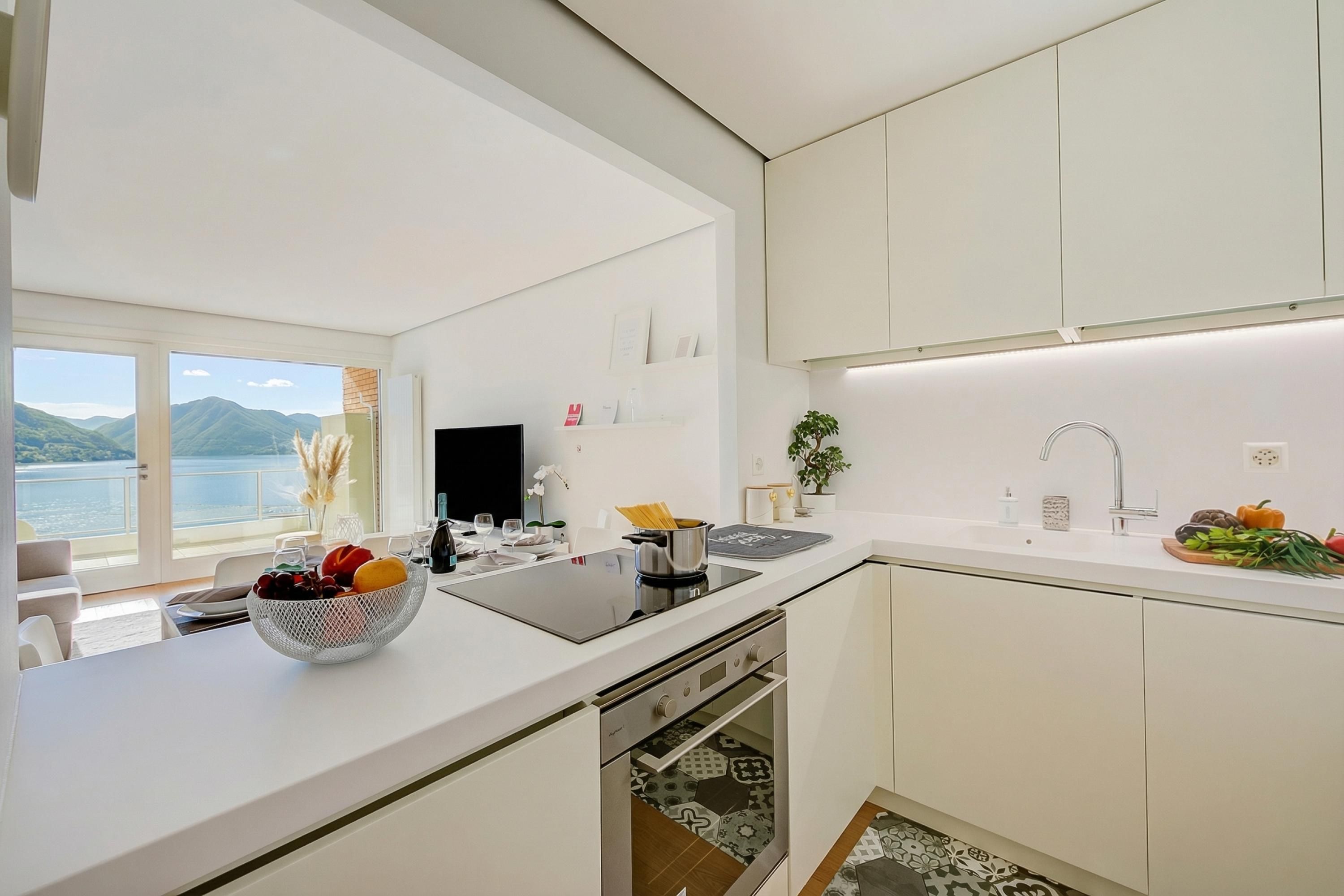 Eine moderne Küche mit einer großen Kochinsel, einem eingebauten Ofen und Seeblick.