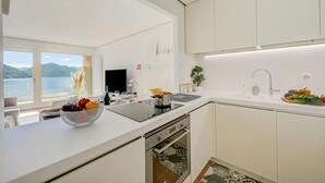 A modern kitchen with a large island, a built-in oven, and a view of the lake. - Honeymoon With Panoramic Lake-view (Lugano)