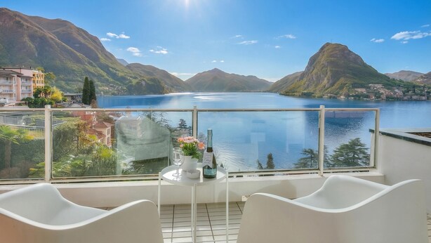 A balcony with a table, chairs, and a bottle of wine. - Honeymoon With Panoramic Lake-view (Lugano)