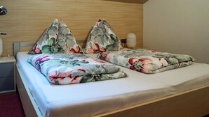 Un lit bien fait, avec une literie à motifs floraux et des oreillers, une tête de lit en bois et une table de chevet avec une lampe.