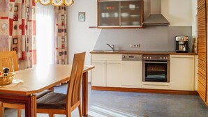 Une cuisine compacte avec un coin repas, comprenant une table en bois, des chaises, une machine à café et un lave-vaisselle.