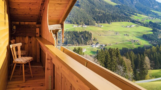 Un balcon en bois offrant une vue sur un paysage montagneux.