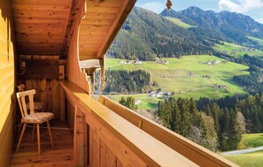 Un balcón de madera con vistas a un paisaje montañoso.