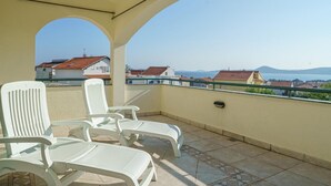 A balcony with two white plastic chairs and a view of houses and mountains in the distance. - Stunning apartment in Vodice with WiFi (Vodice)