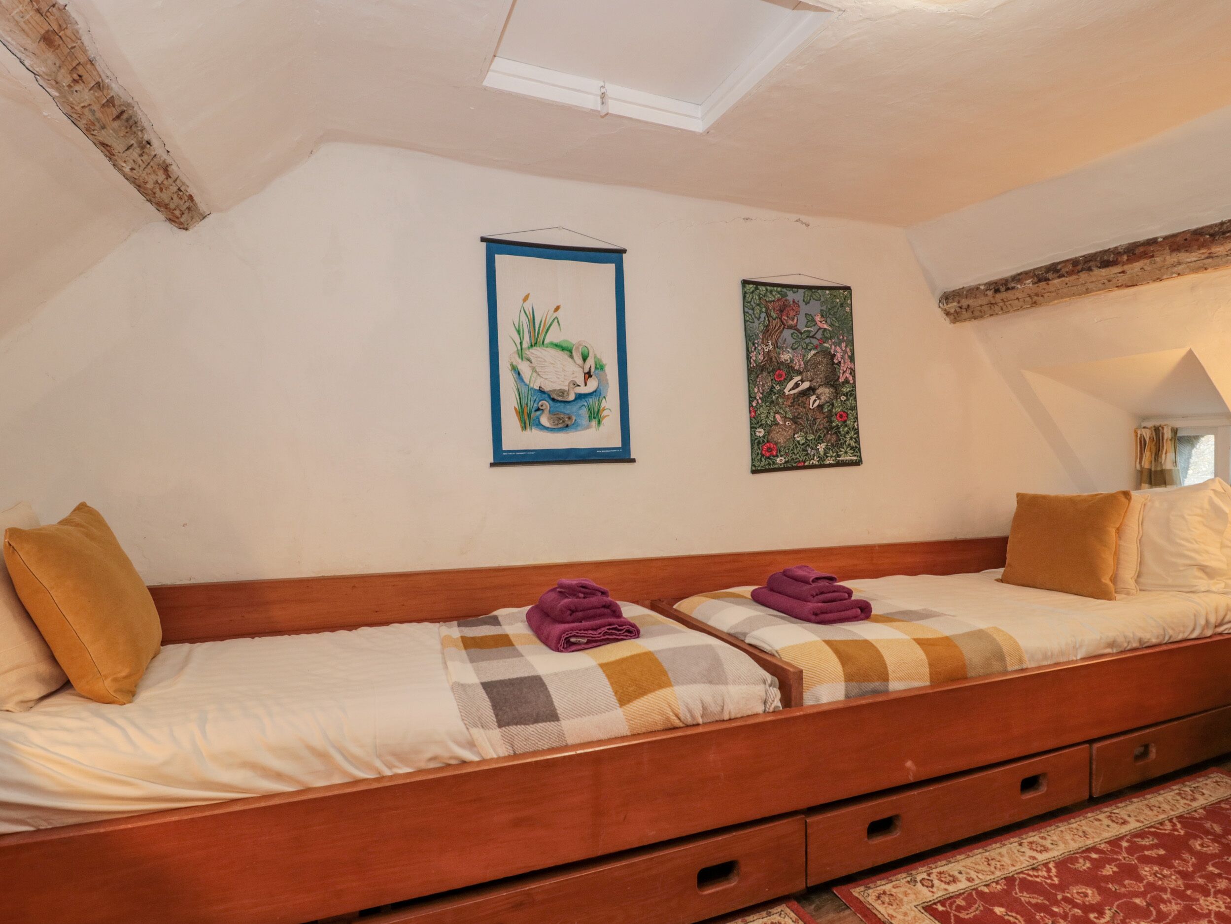 Una camera accogliente con un letto a soppalco e un letto a castello, con una testiera in legno, una coperta a quadri e un tappeto rosso con motivi.
