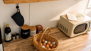 Un comptoir de cuisine sur lequel on trouve divers objets, notamment un four à micro-ondes, un panier d’œufs, une machine à café et plusieurs récipients.