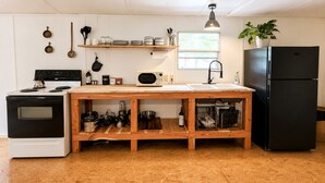 Une cuisine équipée d’une cuisinière, d’un four à micro-ondes, d’un évier et d’un réfrigérateur noir.