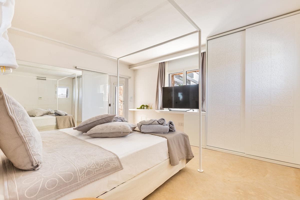 Une chambre à coucher avec un lit, une télévision, une armoire et une fenêtre.