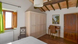 Ein Schlafzimmer mit einem Bett, einem Schreibtisch, einem Stuhl, einem Kleiderschrank und einem Fenster mit Vorhängen.