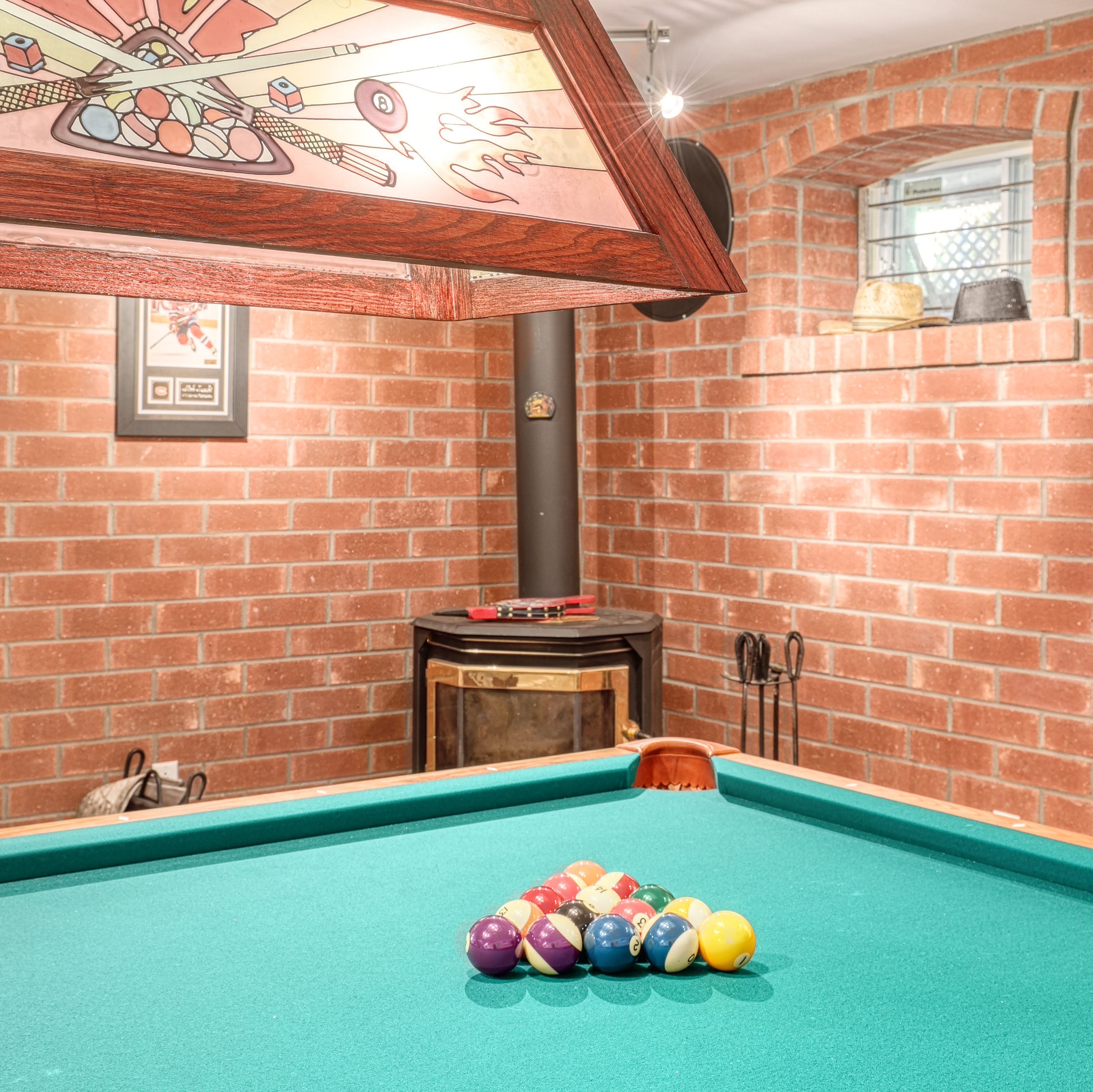 A billiards table with balls, a fireplace, and a brick wall.