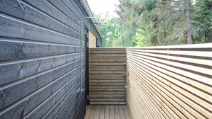 A wooden deck with a metal railing, adjacent to a building with dark siding. - 2 bedroom cozy home in Samsø (Samsø)