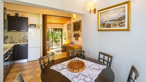 Une cuisine compacte dotée d’appareils électroménagers modernes, un coin repas avec une table ronde et une vue sur un jardin.