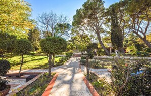 Stroll through the serene garden, surrounded by lush trees and shrubs, leading to a tranquil retreat.