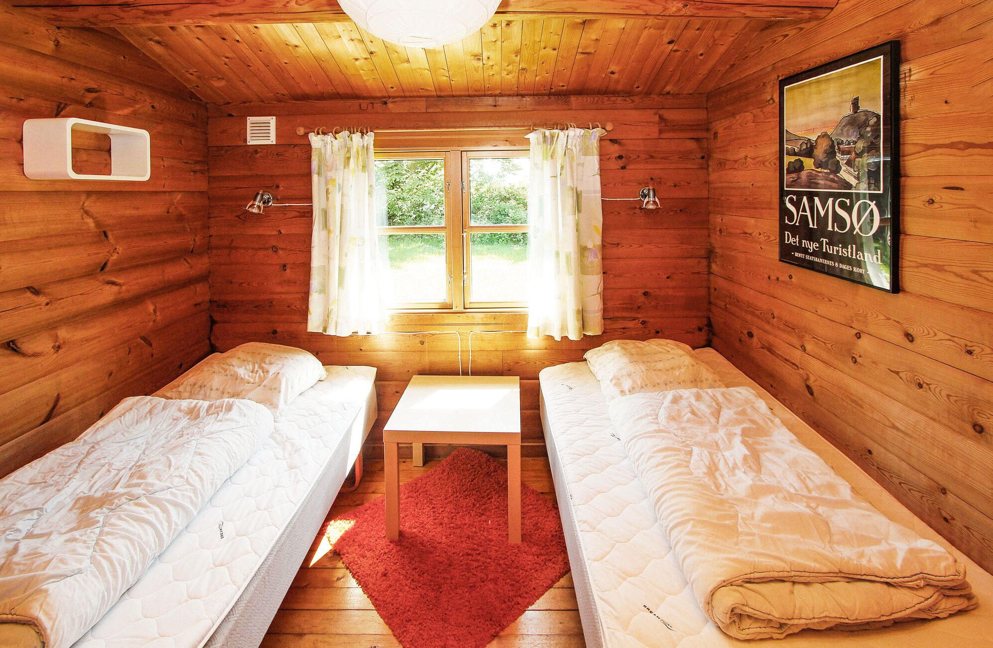 Une cabane confortable avec deux lits, une petite table et une fenêtre avec des rideaux.
