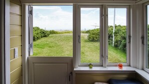Ein Zimmer mit Erkerfenster mit Blick auf einen grünen Rasen.