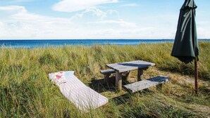 Ein Picknickplatz mit Tisch und Bänken an einer grünen Fläche in der Nähe von Gewässer.