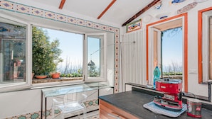 A kitchen with a glass table, a red coffee machine, and a view of the garden through the window. - Awesome home in La Spezia with WiFi (La Spezia)